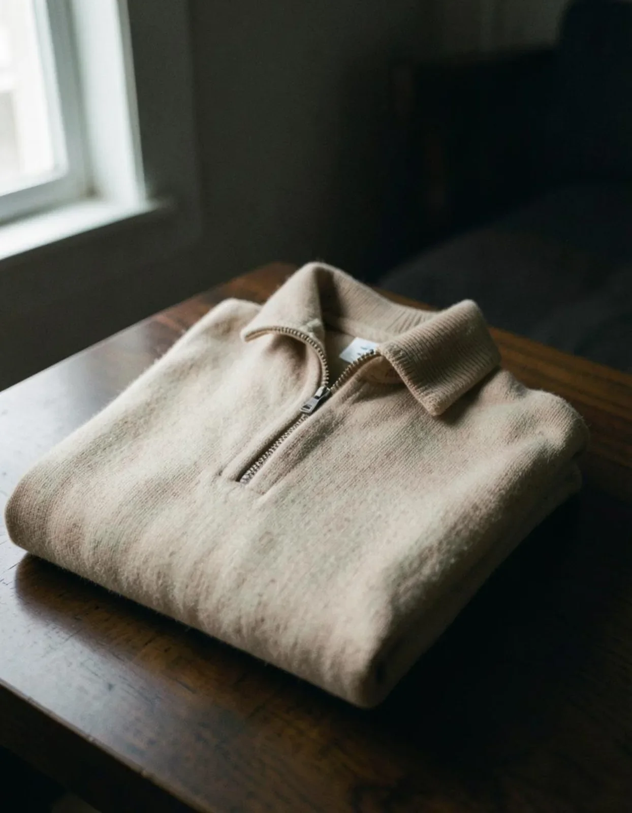 A folded oatmeal quarter-zip sweater.